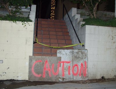 Stairs blocked off with plywood, 'Caution' hastily scrawled across the barricade.