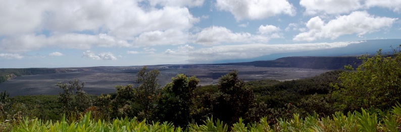 Wide flat area with cliffs rising to the right, treetops in the foreground.