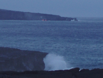 Lava entering the sea at the base of a cliff