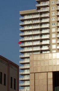 Apartment high-rise with identical balconies... and one red umbrella.