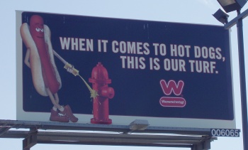 Billboard: When it comes to hot dogs, this is our turf. (Wienerschnitzel mascot sprays mustard on a fire hydrant.)