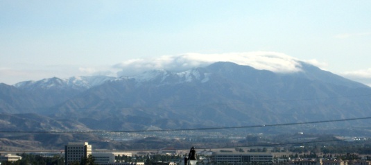 Mt. Saddleback topped with cloud, the peaks next to it covered in snow.