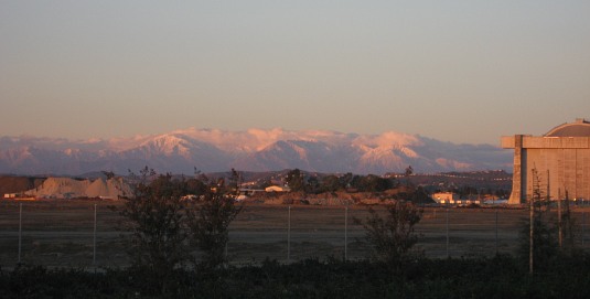 Snow-covered San Gabriels and blimp hangar at sunset