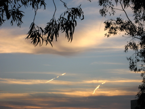 2 contrails and a shadow lit up against the morning sky.