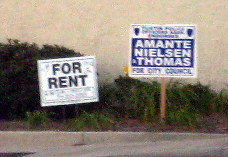 Two signs: For Rent and a campaign sign.