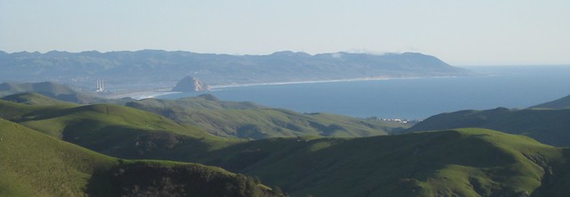 Morro Bay seen from a distance, with green hills in front.
