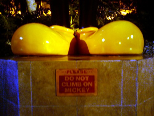 Two giant yellow feet and a sign: Please Do Not Climb on Mickey