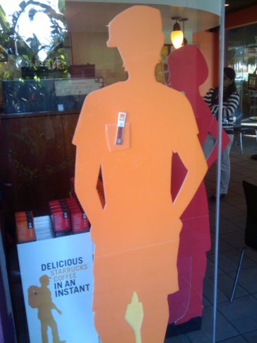 A stand-up orange silhouette of a person in the window of a Starbucks.