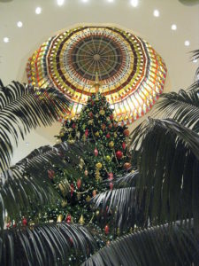 Looking up at a huge Christmas Tree under a dome, flanked by palm trees.