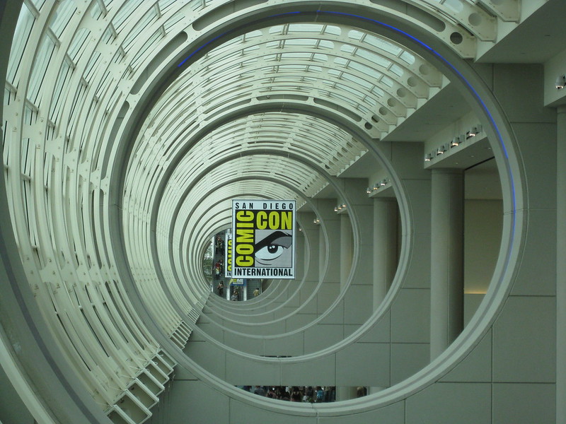 Looking along a long, semi-open tube in a building, with the Comic-Con banner in the center.
