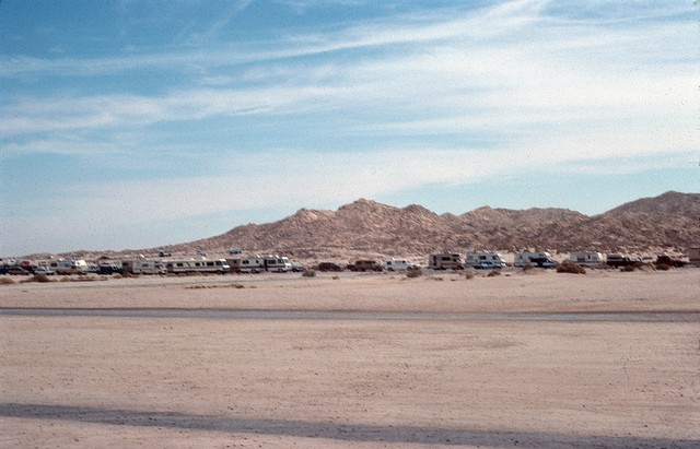 Long line of cars and RVs waiting to get out on a desert road.