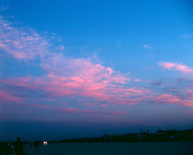Pink clouds, blue sky, and darkness on the ground.