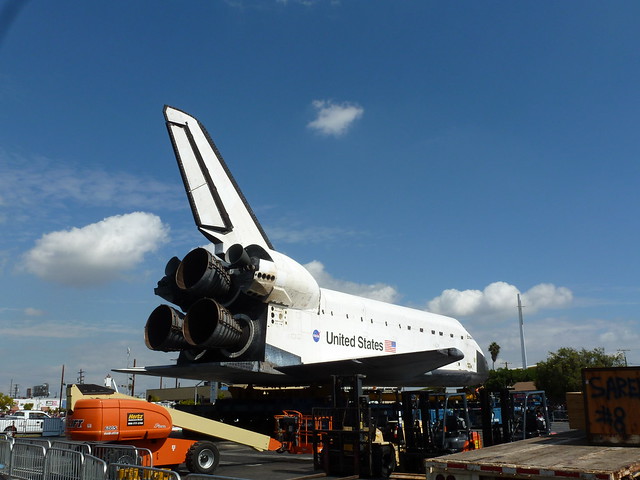 A view of the space shuttle's engines from behing, and some loading equipment.