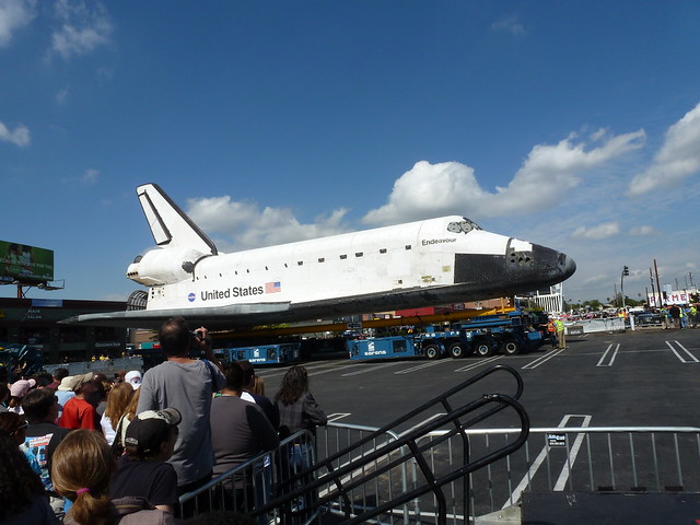 Space shuttle on its transport vehicle in a parking lot, with clear space around it.