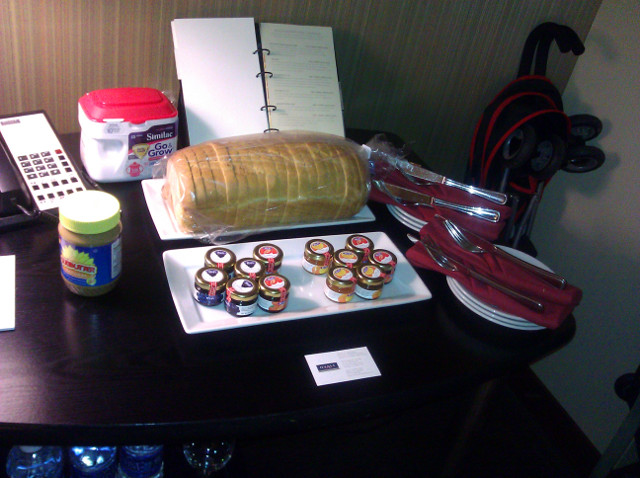 A view of the table with bread, jam jars, place settings, and a jar of Sunbutter.