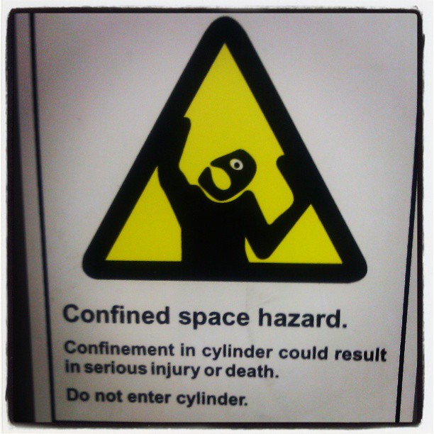 Stick figure trapped in a yellow triangle, hands pressing against the edges, one wide eye visible and a mouth open farther than possible like the whole head is ready to open like a hinge.

Oh, and a warning not to climb into the washer or dryer.