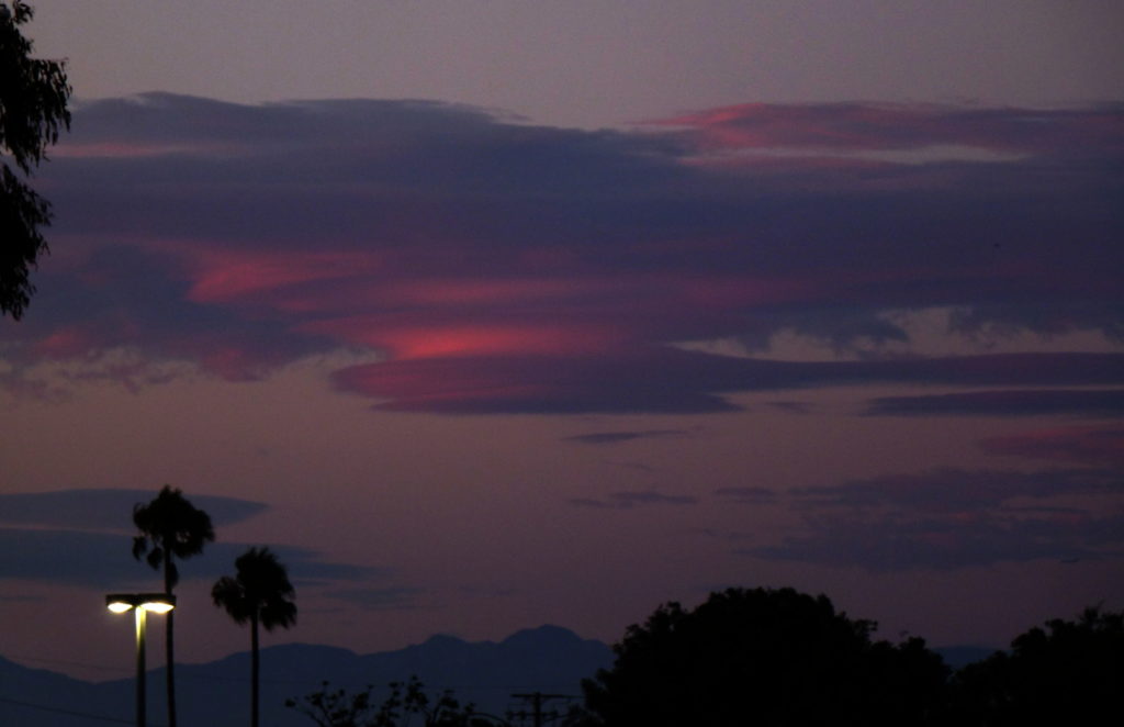 Crimson Saucers: Lenticular clouds at sunset.