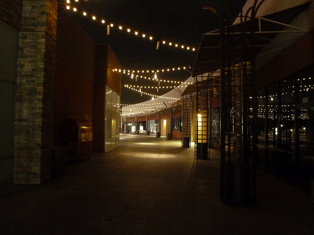 Lights strung across an empty walkway past empty windows.