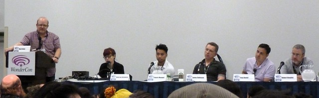 A bunch of comic book writers sitting at a long table with microphones.