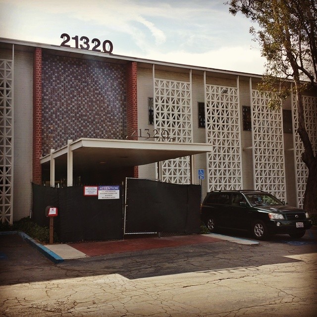 A two-story building with tiles and several vertical screens with square-and-diagonal patterns and an awning.