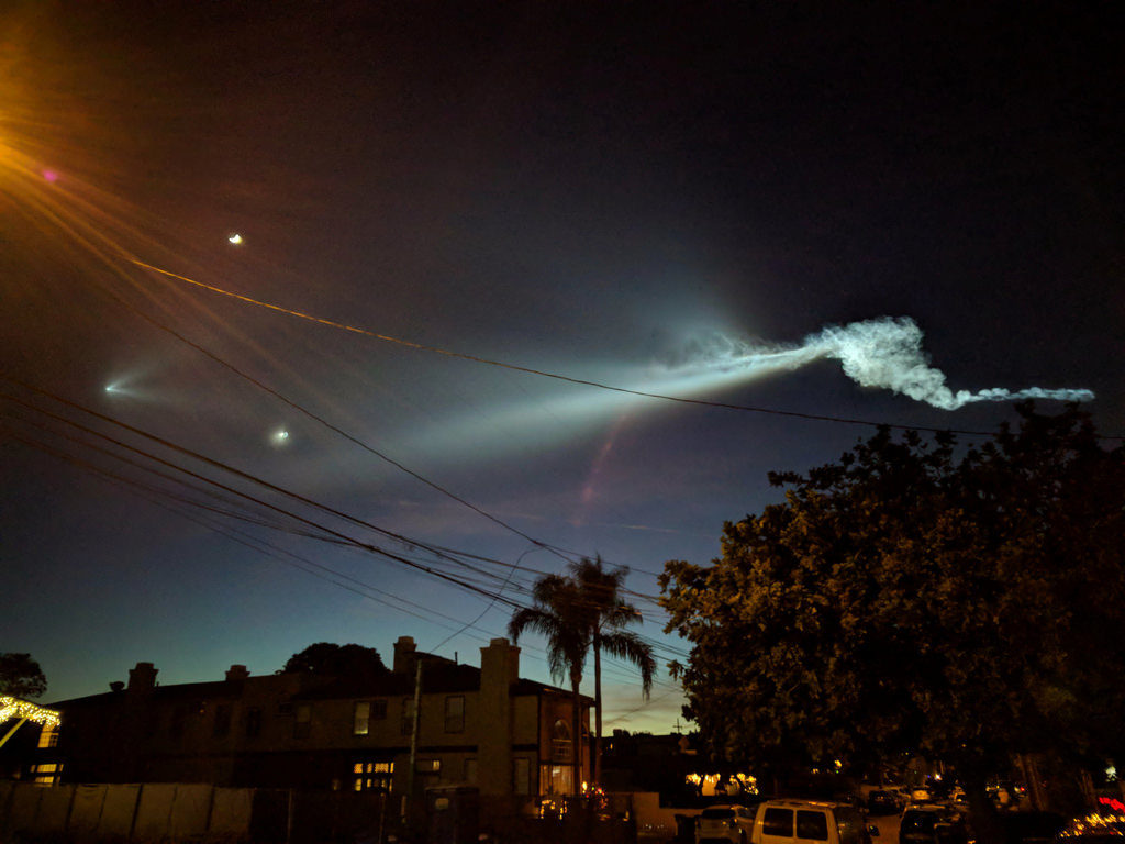 Night sky with *very* bright cloud trail on one side, and on the other, a small bright spot with two tails branching off like a boat's wake.