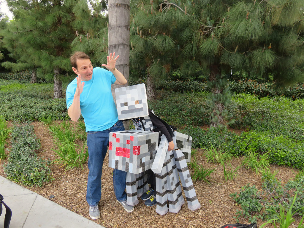 Kid in a skeleton costume with a boxy head, wearing a cardboard-box spider as if the skeleton is riding it, as a Minecraft spider-jockey. And me dressed as Steve.