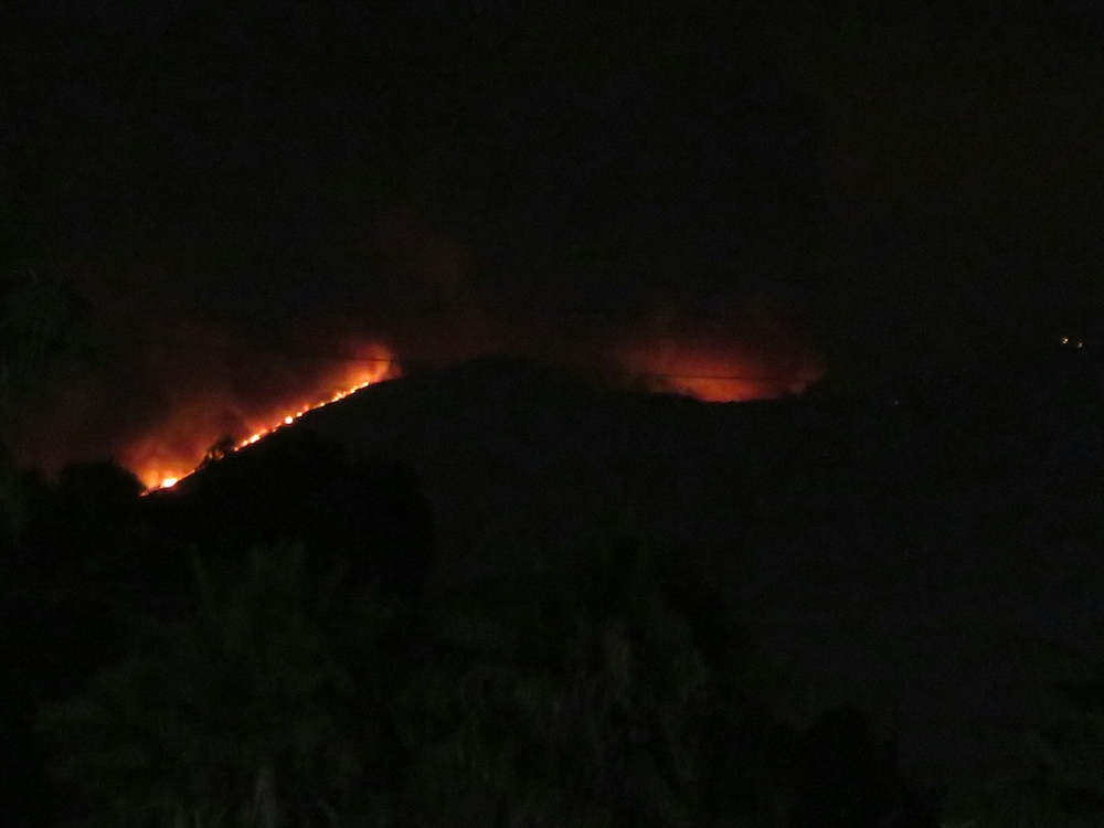 [Night view: Mostly black, with an orange line silhouetting the edge of a mountain.]