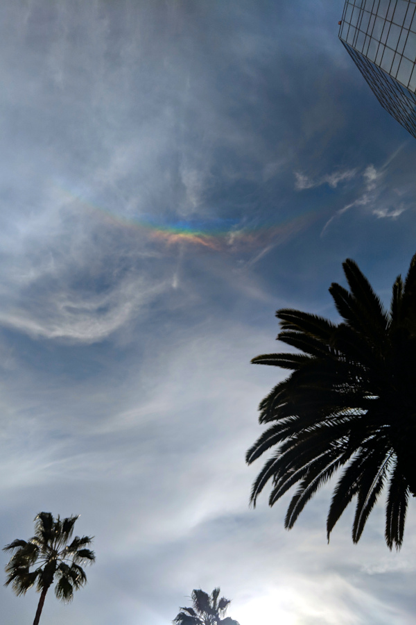 Wispy clouds with an upside-down rainbow near the top of the sky.