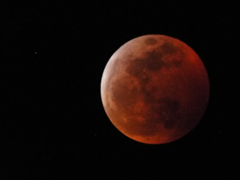 Full moon, mostly red except for a whiter edge at the upper left.