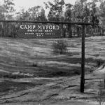 Old photo of Camp Myford gate and sign over a dirt road.