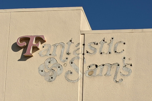 Sign for Fantastic Sam's with all the letters removed except the F. You can see where the older letters were by how the wall was painted around them.