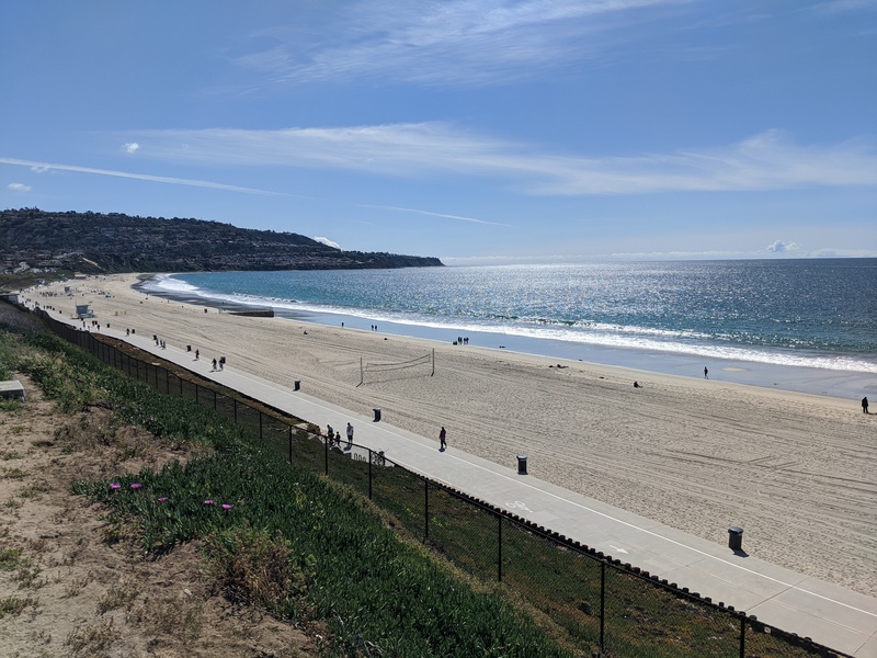 Curve of beach with very few people on it.