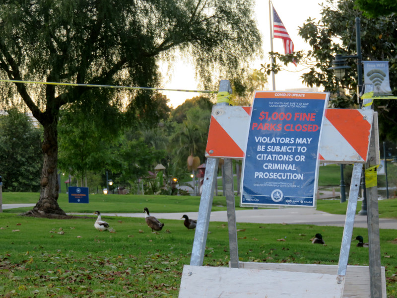 sign saying the park is closed, caution tape, and ducks out away from the pond