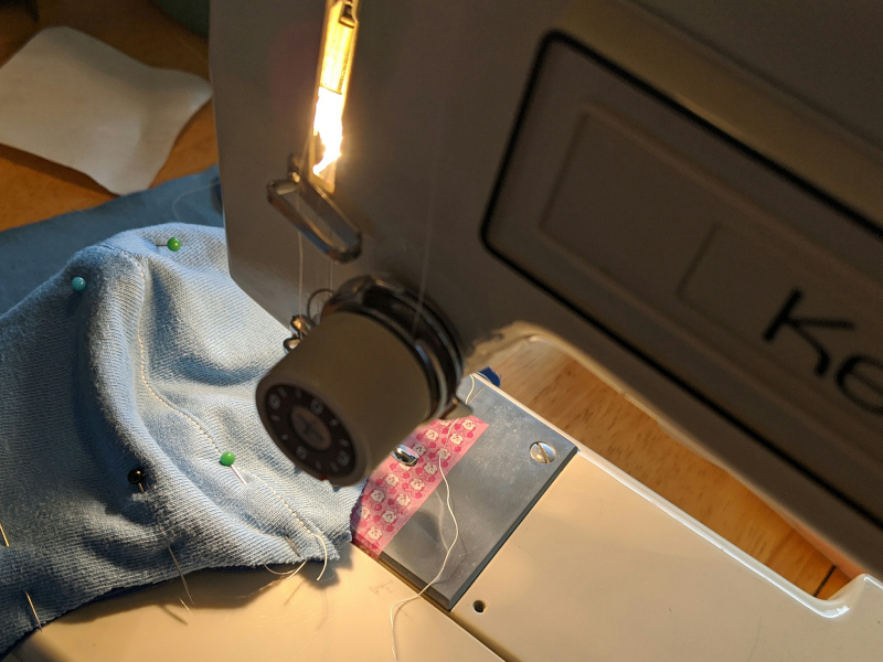 Sewing machine close-up with a face mask in progress.