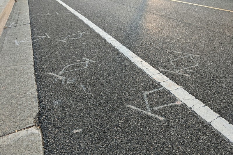 A bunch of diamond-and-bar markings spray painted on a street.