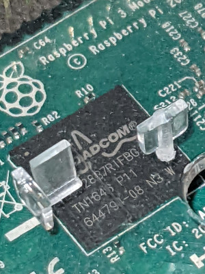 A close-up view of a circuit board with Raspberry Pi 3 written on it and a Broadcom chip partially hidden by plastic spacers.
