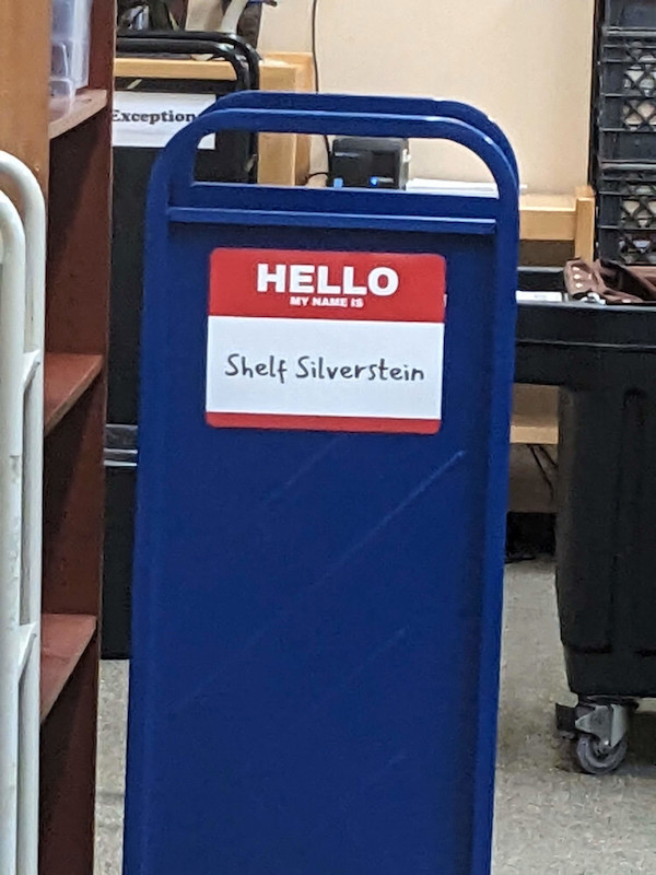 Library cart with a large sign mimicking a 'Hello my name is...' nametag, with 'Shelf Silverstein' written on it.
