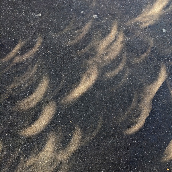 A bunch of overlapping bright crescents of light on the ground.