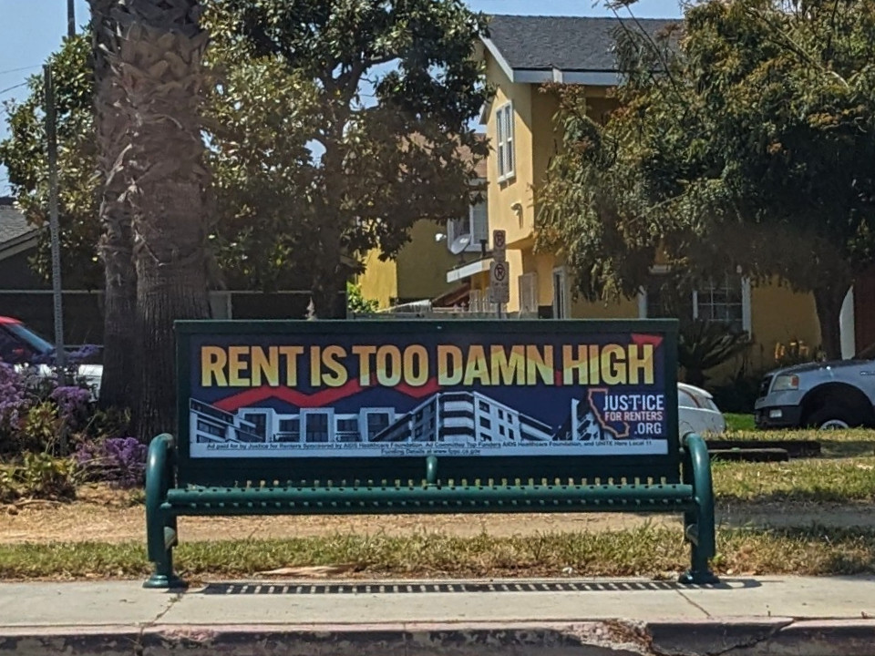 A bus stop bench with the slogan RENT IS TOO DAMN HIGH.