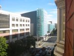 City street during daylight. Across the way a boxy building with trees in front of it. Beyond an intersection is a taller building with a large glass front-pane at the corner labeled METREON. An old-style extruded window area is visible at right, close to the viewpoint.