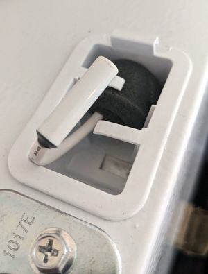 A small cylinder on the end of a wire, sticking out through a hole in a basket set into the top of the refrigerator.