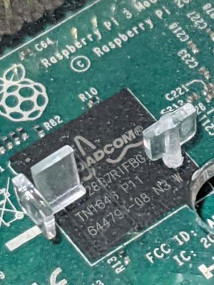 A close-up view of a circuit board with Raspberry Pi 3 written on it and a Broadcom chip partially hidden by plastic spacers.